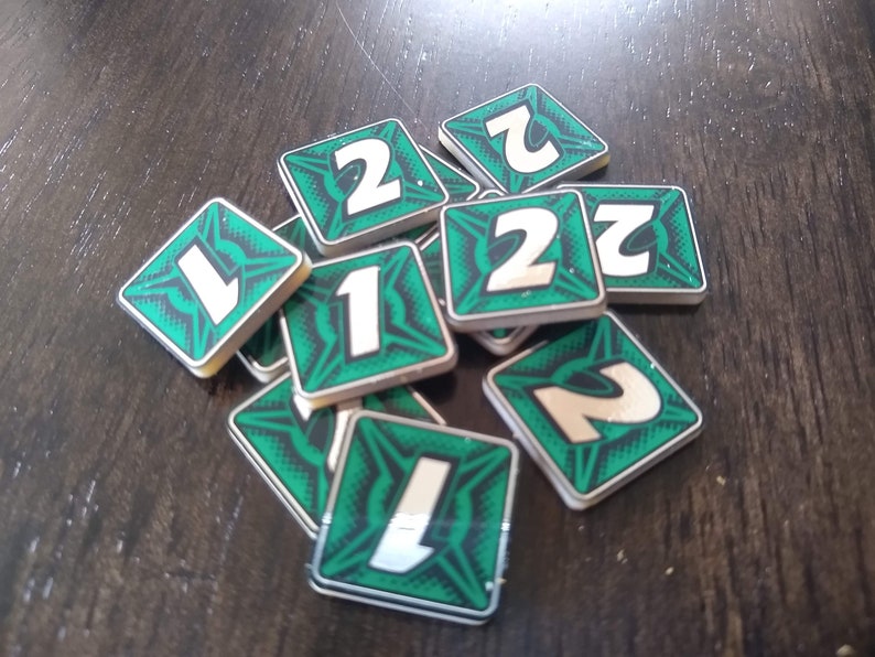 May include: A pile of green and white square tiles with the numbers 1 and 2 printed on them.