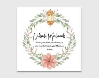 Puede incluir: Una tarjeta blanca con una corona de acuarela de hojas verdes y flores rosas. Una linterna dorada cuelga de la corona. El texto "Nikkah Mubarak" está escrito en caligrafía negra. El texto "Wishing you a lifetime of love, joy and togetherness in your Marriage, Ameen." está escrito en negro debajo de la corona.