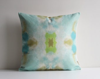 May include: A square throw pillow with a blue, green and white tie-dye pattern.