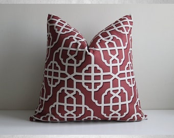 May include: A red and white geometric patterned throw pillow with a white background and a burgundy lattice design.