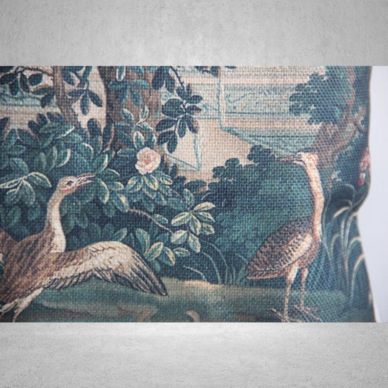 以下が含まれることがあります： 緑と茶色のタペストリーには、庭園の中に2羽の鳥が描かれています。鳥はスタイリッシュで、長い首とくちばしをしています。庭園は緑の葉と1つのピンクの花でいっぱいです。