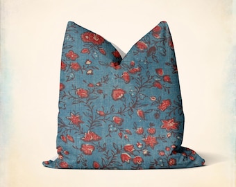 Puede incluir: Una almohada azul con un patrón floral rojo. La almohada está hecha de una tela suave y texturizada.