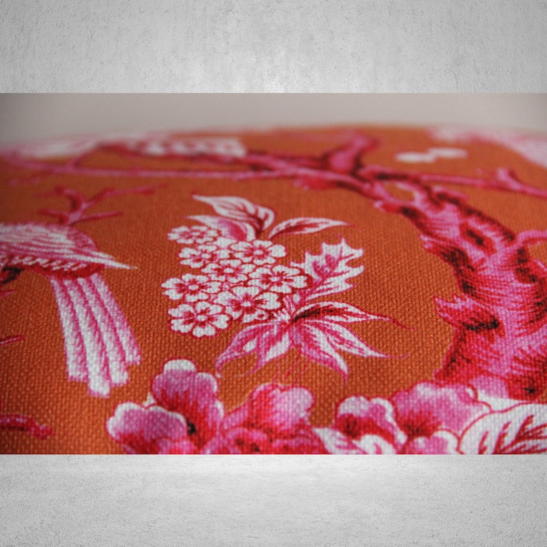 May include: Orange fabric with a pink and white floral pattern. The pattern features birds, flowers, and branches.