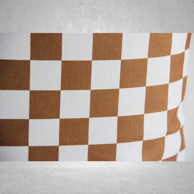 May include: Brown and white checkered throw pillow. The pillow is made of a soft, woven fabric.