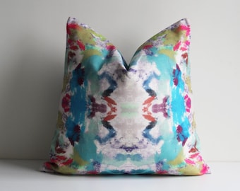 May include: A colourful throw pillow with a blue, green, pink and purple abstract pattern.