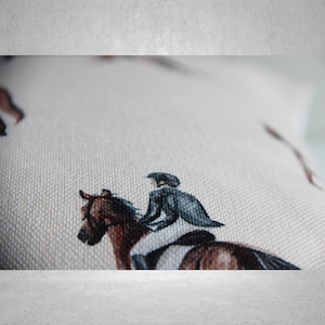 May include: A white cotton pillowcase with a repeating pattern of brown horses and riders in black riding attire. The pillowcase is made of a soft, textured fabric.