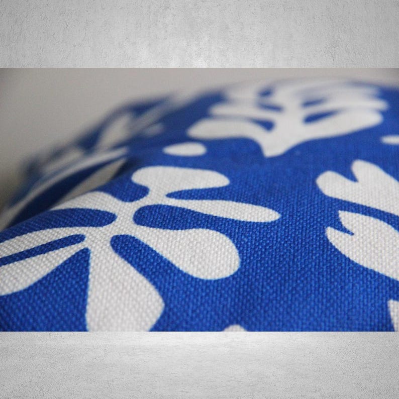 May include: A blue throw pillow with a white floral pattern. The pillow is made of a soft, textured fabric.