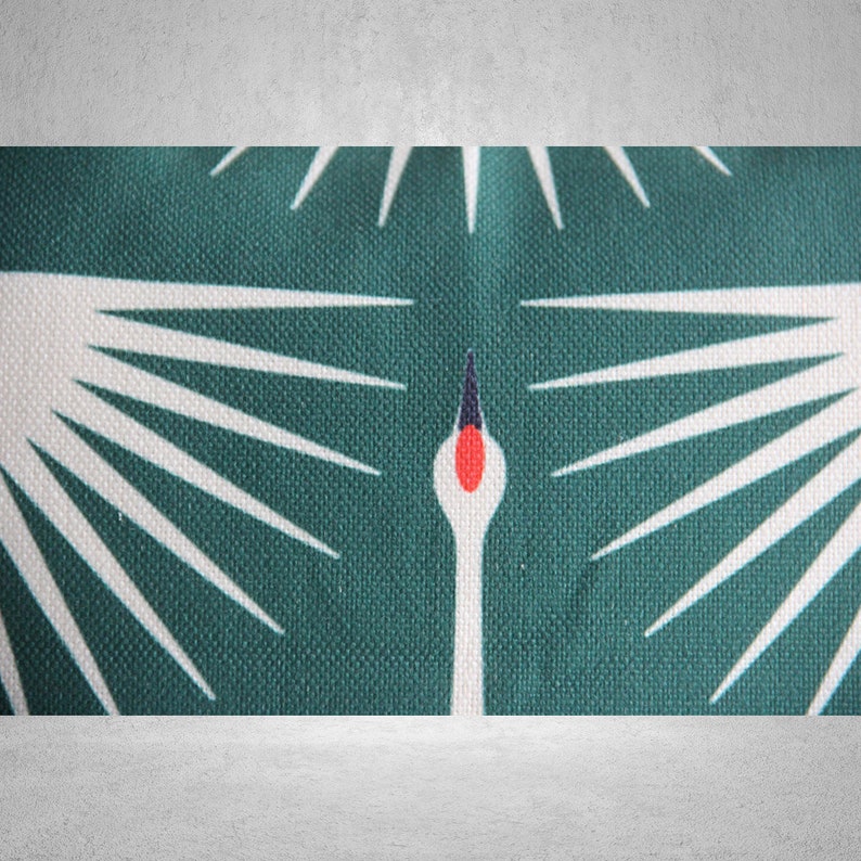 May include: A teal fabric with a white crane design. The crane has a red beak and black eyes. The fabric has a textured surface.