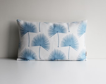 Könnte beinhalten: Ein weißes rechteckiges Kissen mit einem blauen Palmenblatt-Muster. Das Kissen liegt auf einer weißen Oberfläche.