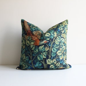 May include: A blue and green cushion with a repeating pattern of a pheasant flying through a leafy tree branch.