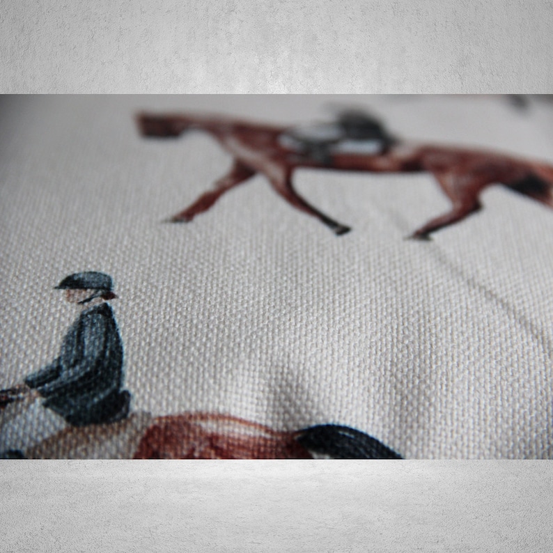May include: A white fabric with a repeating pattern of brown horses and riders. The fabric has a textured surface.