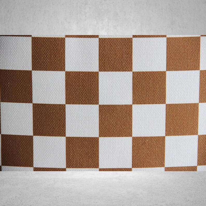 May include: A brown and white checkered pattern on a fabric surface. The fabric has a woven texture.