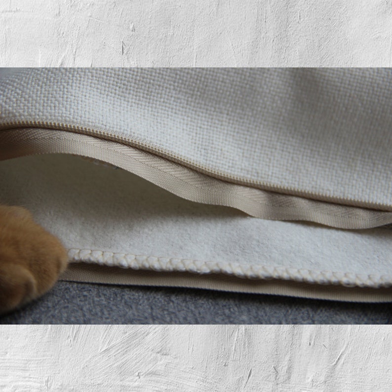May include: Close-up of a white pillowcase with a zipper closure. The pillowcase is made of a soft, textured fabric and has a beige lining.