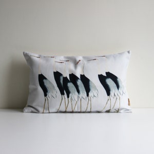Peut inclure: Un oreiller rectangulaire blanc avec un motif noir et blanc de sept grues marchant en ligne. Les grues sont tournées vers le côté droit de l'oreiller.