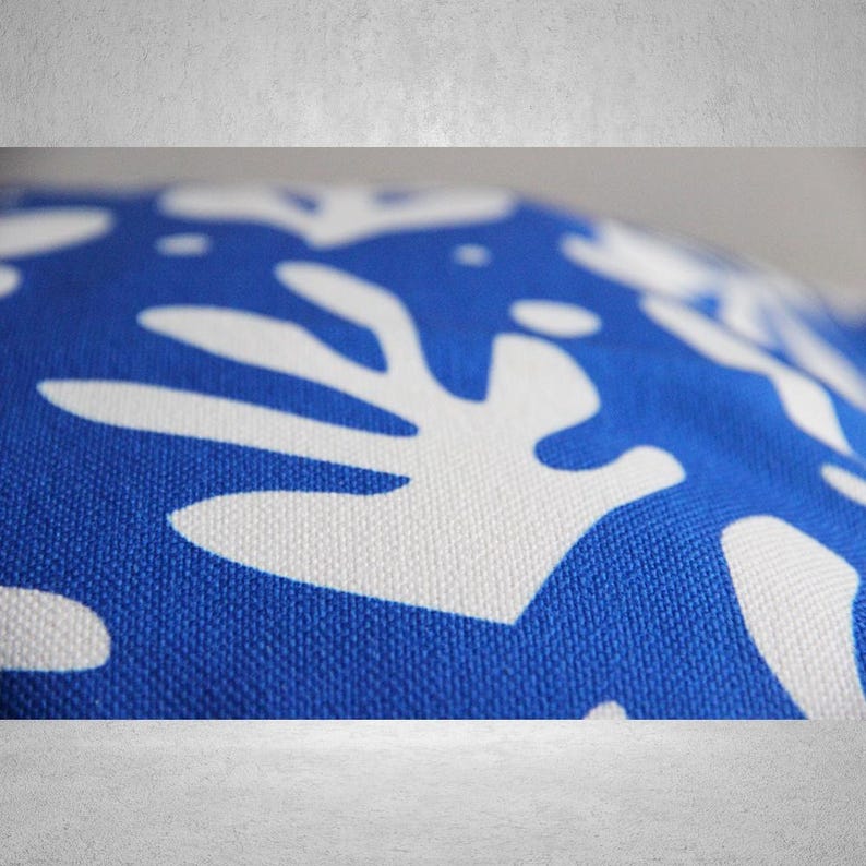 May include: Blue and white patterned fabric with a close-up of a white abstract design. The fabric has a textured surface.