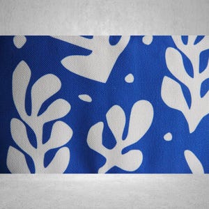 May include: Blue fabric with a white abstract floral pattern. The fabric has a textured surface.