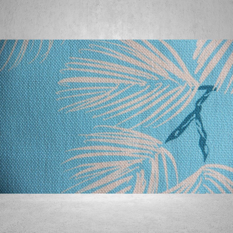 May include: Close-up of a textured, light blue fabric with a repeating pattern of white palm fronds. The fabric has a woven appearance, and the design is reminiscent of tropical themes. The image is well-lit, highlighting the details of the textile.