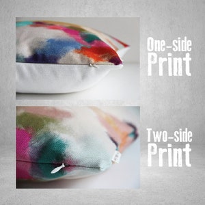 May include: Close-up of two decorative throw pillows with abstract watercolor designs. One pillow features a one-sided print, while the other showcases a two-sided print. The pillows have a white background and a zipper closure.