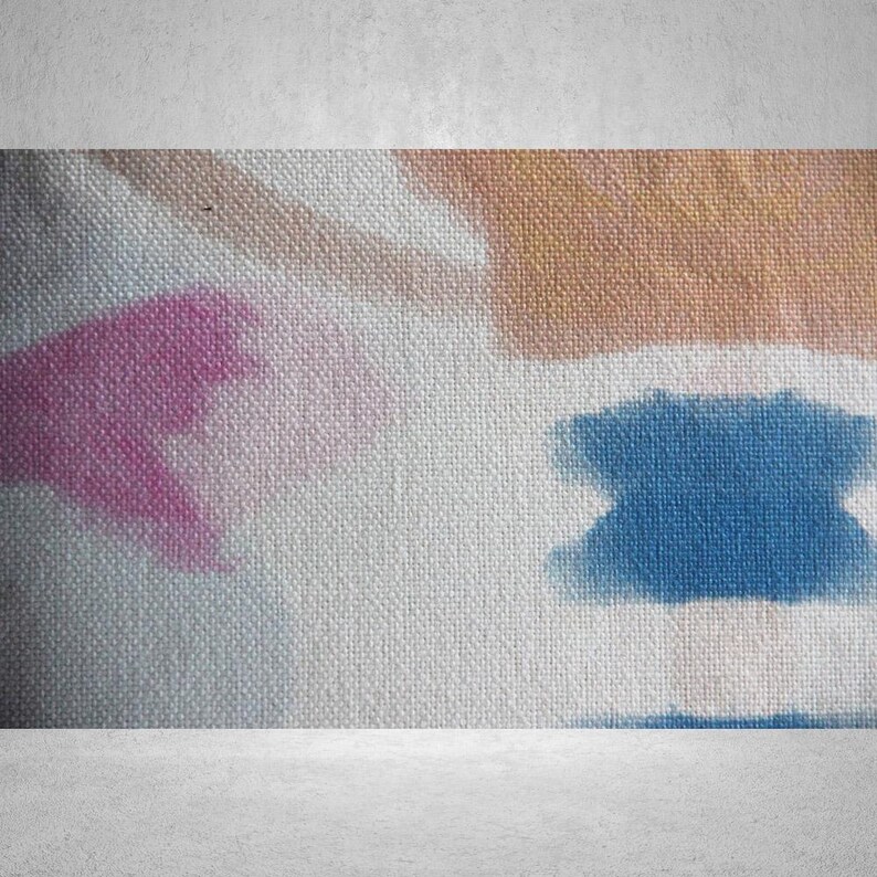 May include: A close-up of a white canvas with a textured surface. The canvas has abstract designs in pink, blue, and brown.