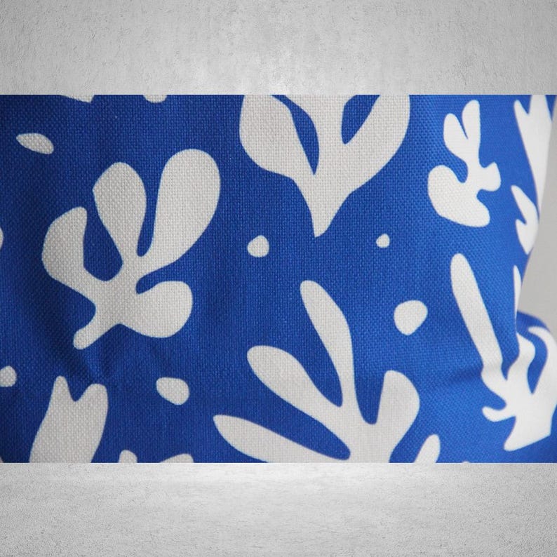 May include: Blue fabric with a white abstract pattern of leaves and shapes.