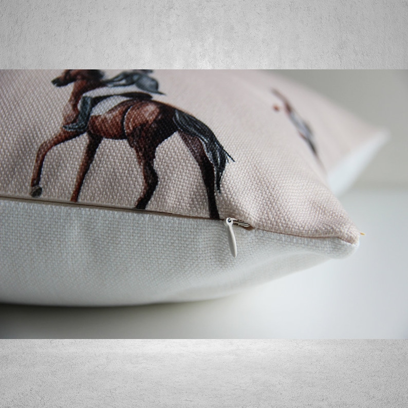 May include: A beige cushion with a zipper closure. The cushion features a repeating pattern of horses and riders.