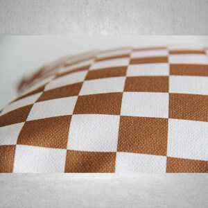 May include: A brown and white checkered pillow with a soft, textured fabric.