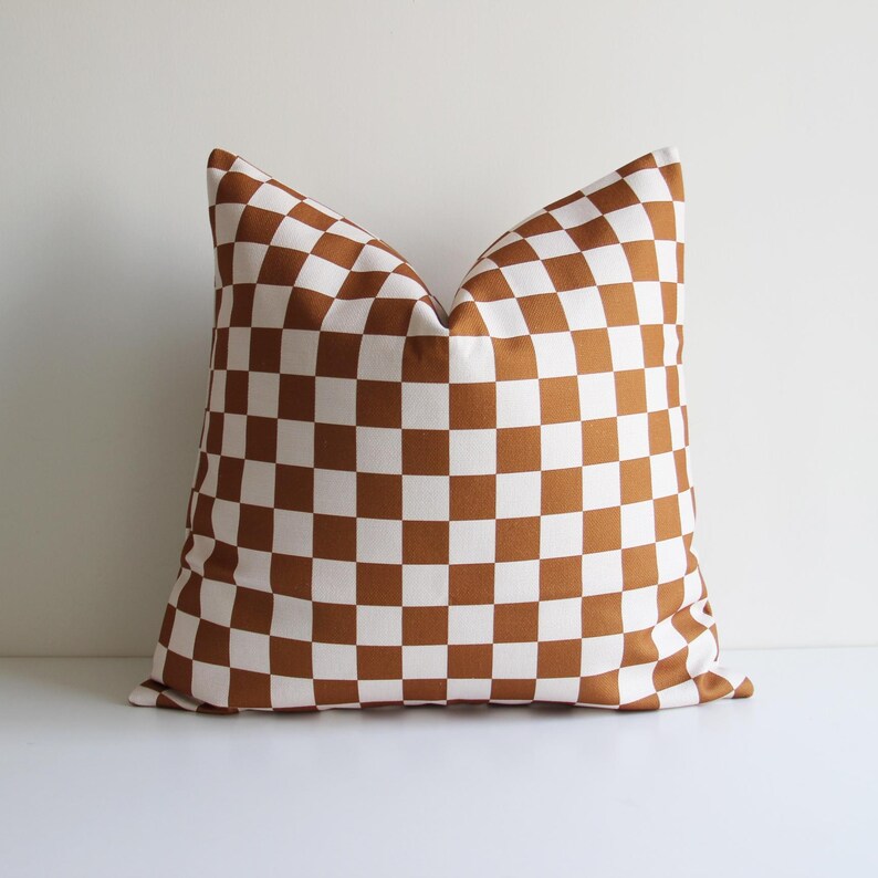 May include: A brown and white checkered throw pillow. The pillow is made of a soft, woven fabric and has a square shape.