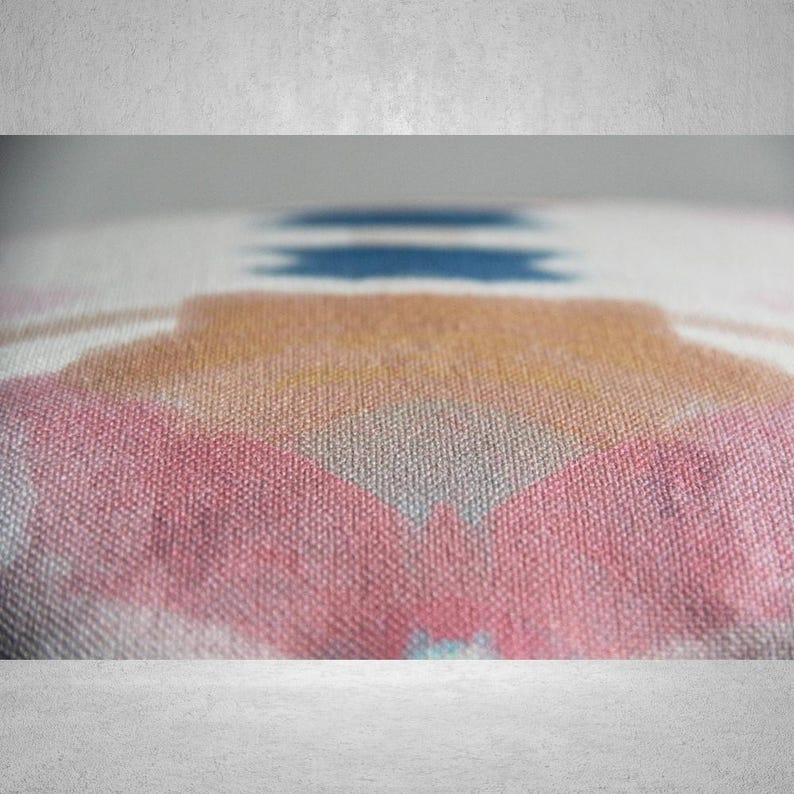 May include: Close-up of a pink, blue, and orange patterned throw pillow with a textured fabric.