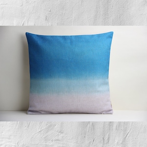 Peut inclure: Un coussin de décoration bleu, blanc et gris avec un tissu doux et texturé.