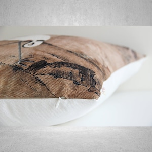May include: A brown and white throw pillow with a zipper closure. The pillow features a vintage-style illustration of a bird in flight.