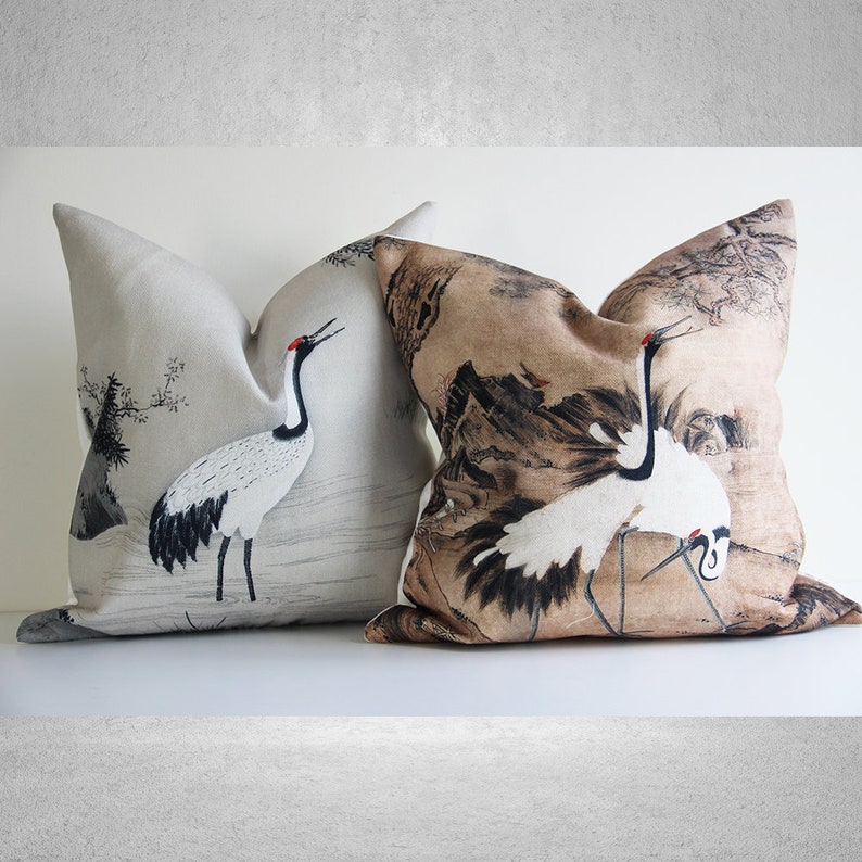 May include: Two decorative throw pillows with a Japanese crane design. One pillow is beige with a black and white crane, the other is gray with a black and white crane.