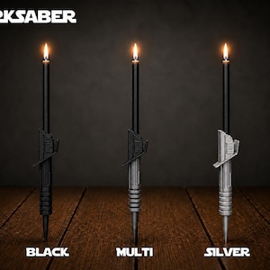 May include: Three black taper candles with hilt-shaped bases labeled DARKSABER. The hilts are black, multi-colored, and silver. Each candle is lit with a small flame at the top. The labels below read BLACK, MULTI, and SILVER in white text.