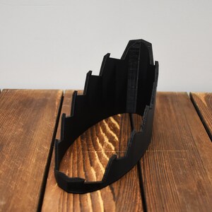 Puede incluir: Objeto de plástico negro impreso en 3D con un diseño escalonado. El objeto tiene forma de semicírculo y un acabado liso y mate.