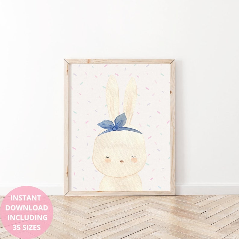 Op de afbeelding: Waterverfillustratie van een cr&egrave;mekleurig konijn met een blauwe strik, omlijst in een licht houten frame. De achtergrond is wit met pastelkleurige confetti. De tekst "INSTANT DOWNLOAD INCLUDING 35 SIZES" staat in een roze cirkel linksonder.