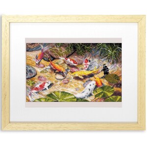 May include: Framed cross-stitch artwork depicting a pond scene with colorful koi fish. The fish are orange, yellow, white, and black, swimming among lily pads and rocks. The artwork is framed in a light wood frame.
