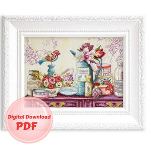 May include: A cross-stitch pattern featuring a still life of a bird, flowers, and various bottles and jars on a table. The pattern is framed in a white frame with a decorative border.