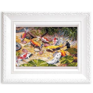 May include: A framed cross-stitch artwork depicts a pond scene with colorful koi fish. The fish are orange, yellow, white, and red, swimming among lily pads and rocks. The frame is white with a decorative edge.