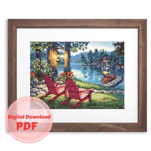 May include: A framed cross-stitch embroidery depicting a lakeside scene with two red Adirondack chairs, a small cabin, and a boat on the water. The scene is set in a forest with green trees and a blue sky.