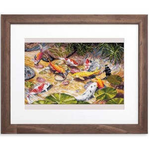 May include: A framed cross-stitch artwork depicting a pond scene with colorful koi fish. The fish are orange, white, yellow, and black, swimming among lily pads and rocks. The frame is a dark brown wood.
