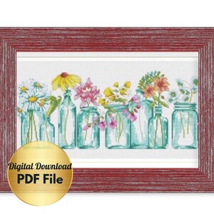 May include: Cross stitch pattern featuring a row of mason jars filled with colorful flowers. The jars are arranged in a row on a white background. The pattern is framed in a red wooden frame. The text "Digital Download PDF File" is displayed in a gold circle.
