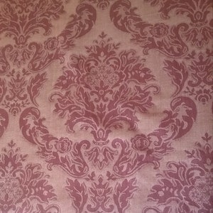 May include: A close-up of a pink fabric with a damask pattern. The fabric has a subtle sheen and a textured surface.