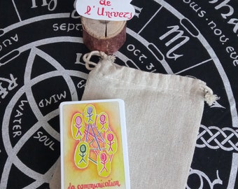 Può includere: Una carta bianca con un'illustrazione colorata di figure stilizzate collegate da linee. La carta ha il testo "la communication" in basso. La carta è appoggiata su una borsa di stoffa beige. La borsa è appoggiata su una superficie nera con un disegno circolare.