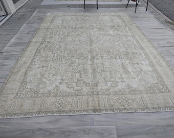 May include: A large, rectangular area rug in shades of beige and gray. The rug features an intricate, symmetrical pattern with a central medallion and detailed borders. The design includes geometric and floral elements, creating a traditional aesthetic.