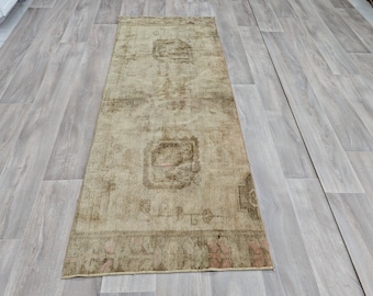 May include: A vintage runner rug with a faded floral pattern in shades of beige and brown. The rug has a distressed look and is perfect for adding a touch of rustic charm to any room.