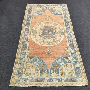 May include: A vintage rug featuring a central medallion in shades of blue and beige, surrounded by a border of intricate floral and geometric patterns in shades of blue, beige, and pink. The rug has a faded, distressed look, adding to its vintage charm.