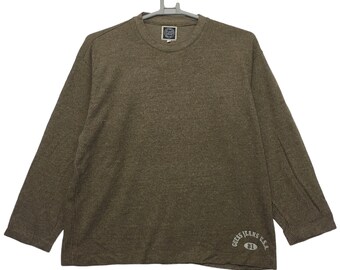 Könnte beinhalten: Ein braunes Langarmshirt mit gerippter Struktur und dem Text "GUESS JEANS U.S.A. 81" unten rechts.