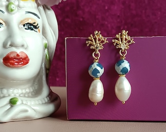 May include: Gold earrings with a blue and white patterned bead and a pearl drop.