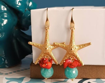 Puede incluir: Pendientes de estrella de mar dorados con coral rojo y cuentas turquesa. Los pendientes son colgantes y tienen un cierre de gancho dorado.