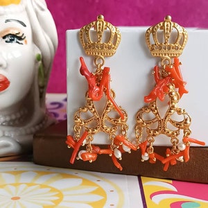 May include: Gold crown dangle earrings with red coral and white pearl accents.