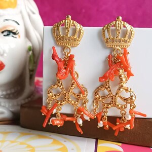 May include: Gold crown earrings with dangling coral and pearl accents.
